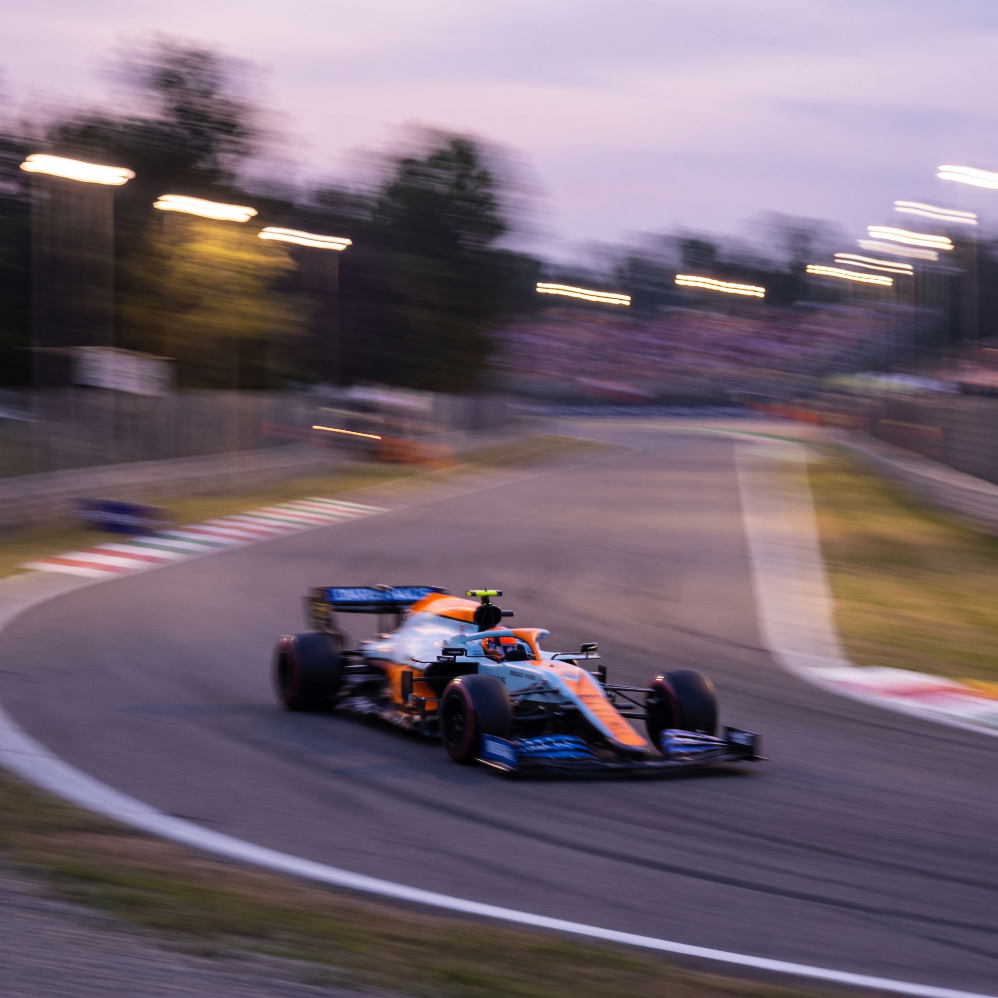 ethereal motion blur style, of a formula 1 car along a racetrack. It is captured mid-turn on an asphalt track with motion blur emphasizing speed.