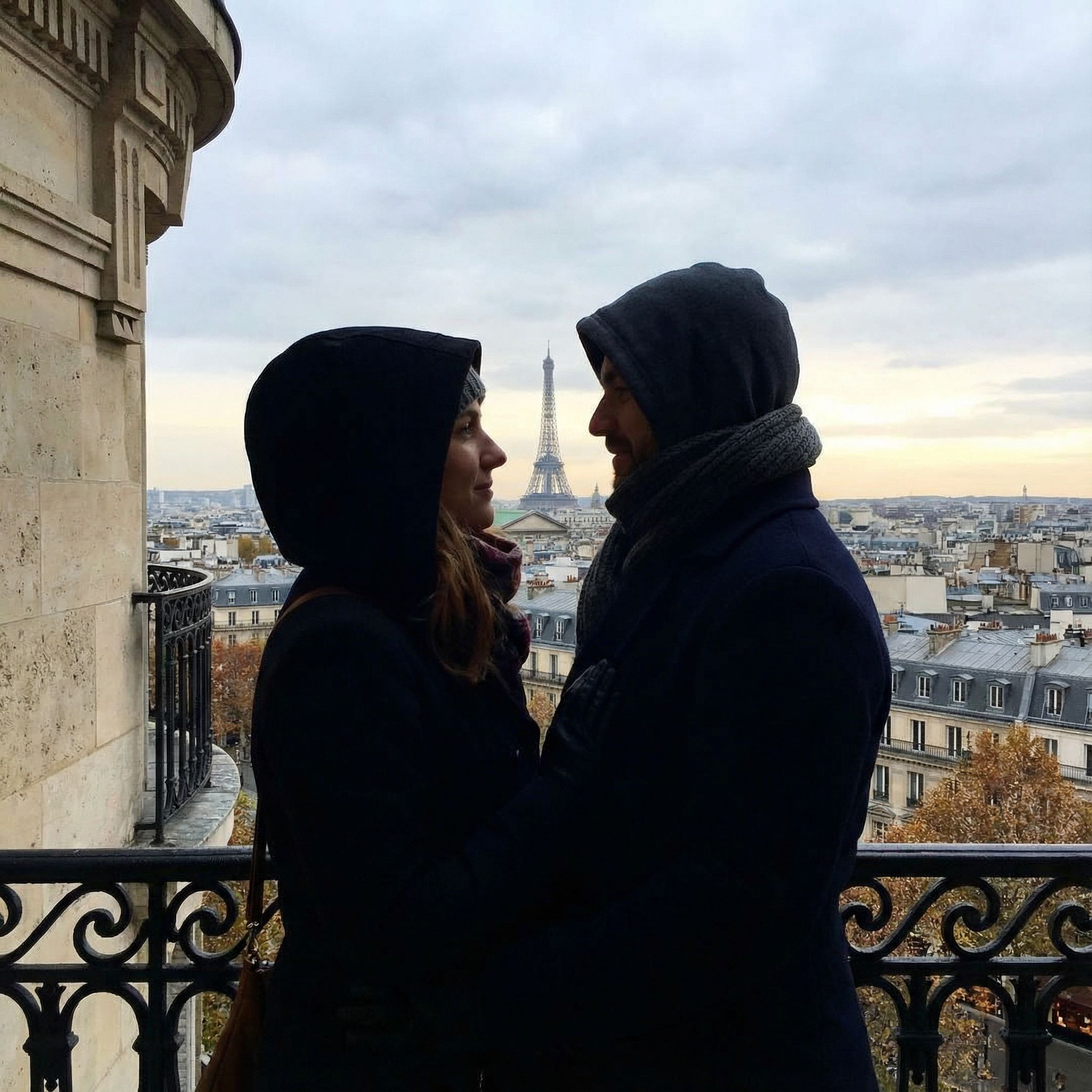 Generate a photo of a couple standing at a height facing each other with only their faces visible. In between them you can see the Eiffel tower in the background.